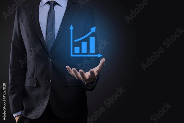 Fototapeta Businessman holding tablet and showing a growing virtual hologram of statistics, graph and chart with arrow up on dark background. Stock market. Business growth, planing and strategy concept.