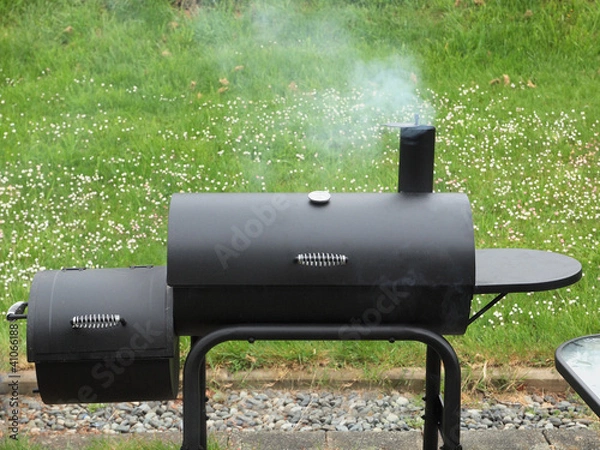 Fototapeta Backyard barbequing on a charcoal smoker