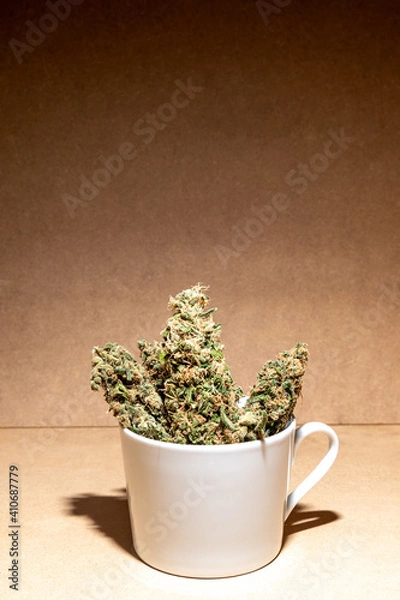 Fototapeta Medical marihuana buds inside a coffee cup. Selective focus.