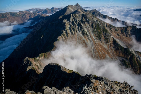 Fototapeta 信州、北アルプス、穂高連峰、北穂高岳（標高3,106m ）山頂の道標と雲海に浮かぶ槍ヶ岳、大キレット、南岳、大喰岳。青空。	