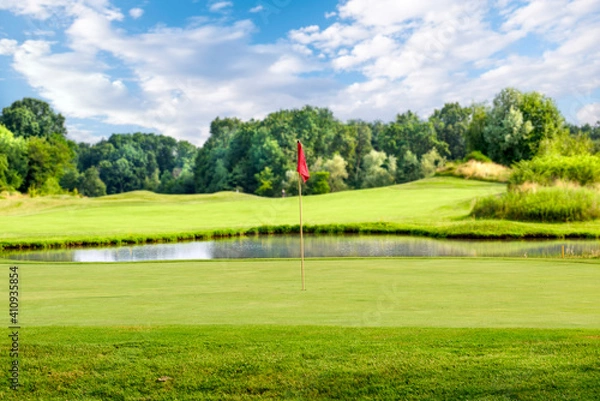 Fototapeta Golf course with a red flag on a summer day