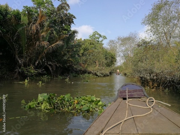 Fototapeta Green and lush backwaters of the river Mekong with a dettail of a wooden row boat