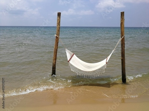 Obraz White textile hammock on woodem poles in the beach, in the water
