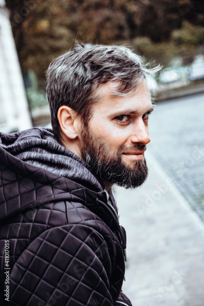 Obraz Artistic photo portrait confident smiling handsome middle-aged Caucasian man portraited in the city, with white skin, grey and black hair having a friendly look on his face, wearing a blue jacket.