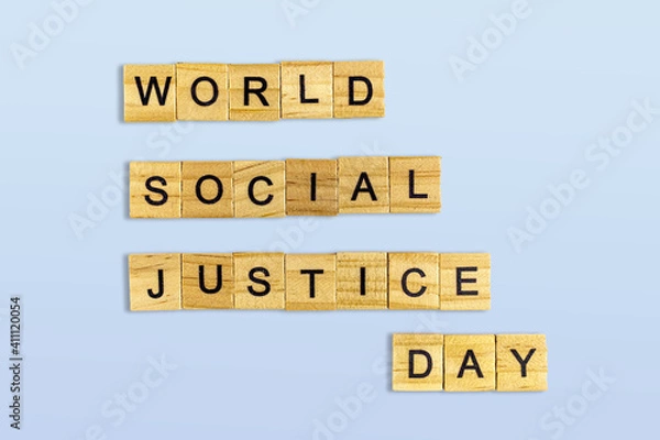 Fototapeta Top view of the word world social justice day laid out from square wooden tiles isolated on blue background. World and international day.