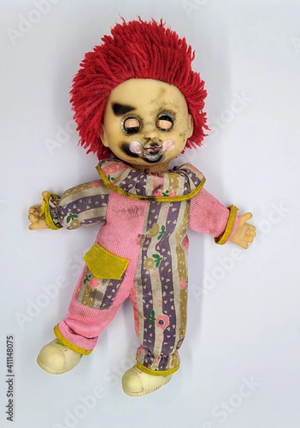 Obraz scary and old battered clown doll with burnt face and red hair on the background of white color top view