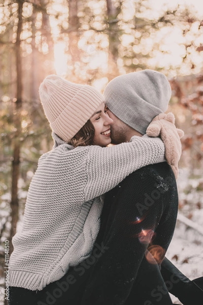 Fototapeta 
Woman hugs a man dressed in mittens in a pine forest