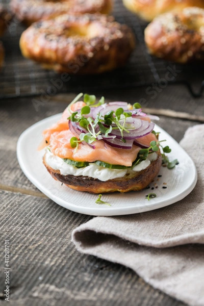 Fototapeta Smoked salmon bagels sandwich with soft cheese and micro greens on a cutting board.