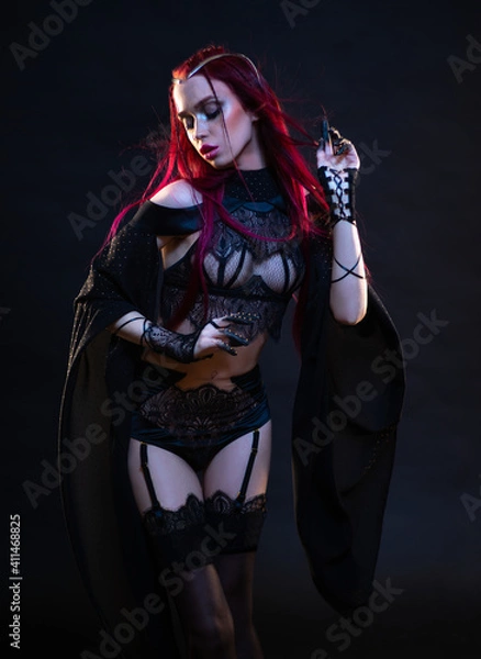Obraz Redhead vampire woman posing on black background in lace lingerie and heels