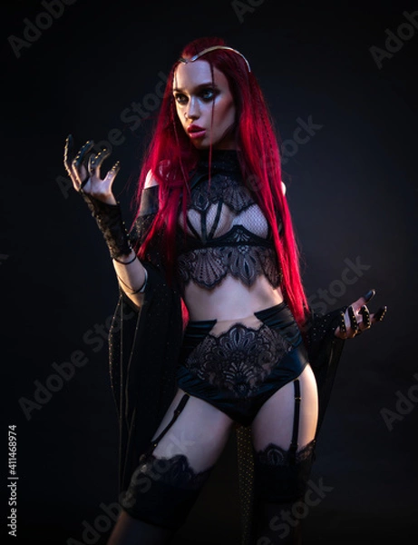 Obraz Redhead vampire woman posing on black background in lace lingerie and heels