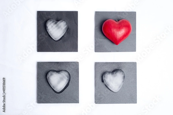 Fototapeta One red love heart and 3 hearts made of ice, placed on 4 slate plates, on a white background. Graphic and geometric, concept of love