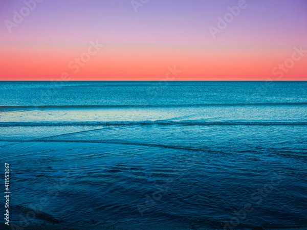 Fototapeta Tranquil Turquoise and Red Colored Seascape at Twilight with Diverging Wave Patterns