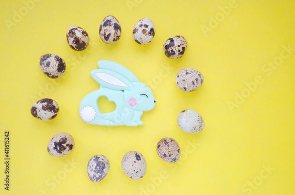 Fototapeta Festive photo with Easter bunny and quail eggs. Top view on a yellow background. Easter. Copyspace.