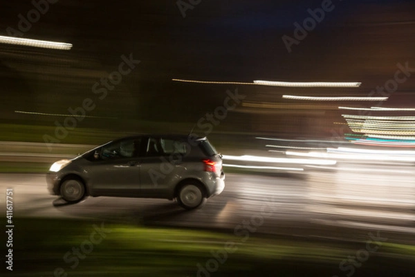 Fototapeta Car traveling at night in urban traffic, blur effect to simulate motion at high speed, concept of danger and drunk driving