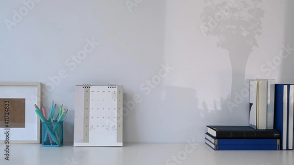 Fototapeta Stylish workspace with calendar, books, stationery and copy space on white table.