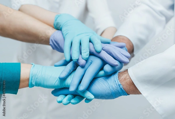 Obraz Team of young doctors stacking hands in blue gloves indoor.  medical teamwork.