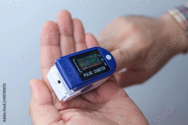 Obraz A man checks his oxygen level using an oximeter