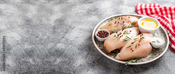 Fototapeta Raw uncooked chicken breasts on grey concrete background, chicken meat with ingredients for cooking. Copy space