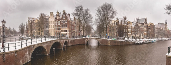 Fototapeta Winter snow view of Dutch canal and old houses in the historic city of Amsterdam, the Netherlands