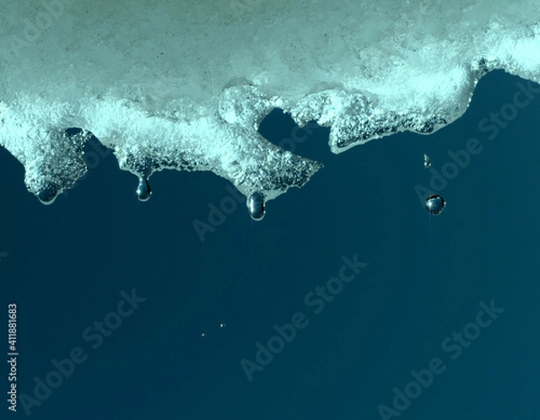 Fototapeta Springtime, ice melting and drops falling reflecting environment and deep blue sky