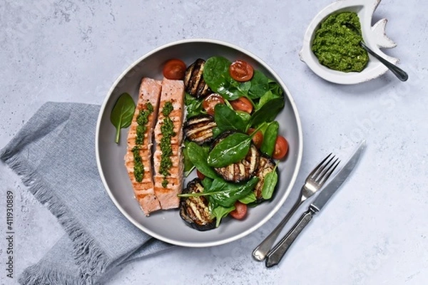 Fototapeta Grilled salmon with aubergine, tomato and spinach salad. Healthy dinner on the light background