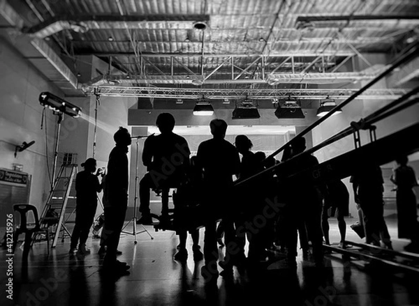 Fototapeta Blurred behind the scenes of music video shooting production crew team silhouette and camera equipment in studio. Black and White.