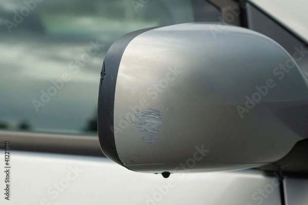 Fototapeta The consequences of a small car accident. Side rearview mirror with scratches and chipped close-up. Repairs are required at the service station. Insurance against accidents.