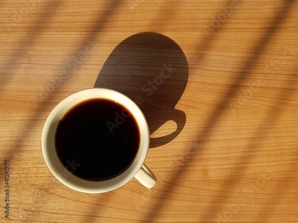 Obraz Top view of coffee cup on wooden table with natural light and shadow in the morning.