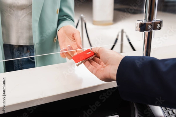 Fototapeta Cropped view of hotel manager giving key to woman in lobby
