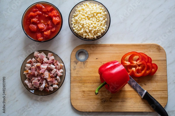 Obraz Cooking at home concept: cutting board, knife, bacon, red peppers, tomatoes and cheese
