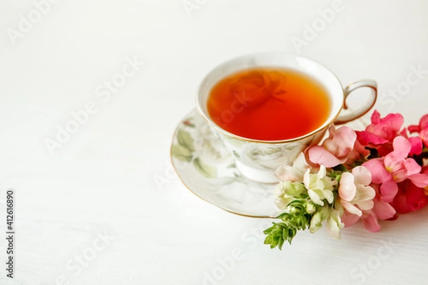 Obraz Porcelain cup of herbal tea and flowers on light background. Selective focus, soft focus. copy space