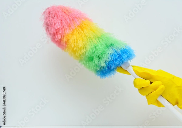 Obraz A woman's hand in a yellow rubber glove. There's a feather duster in this hand. White background. Concept-hygiene, maintaining cleanliness