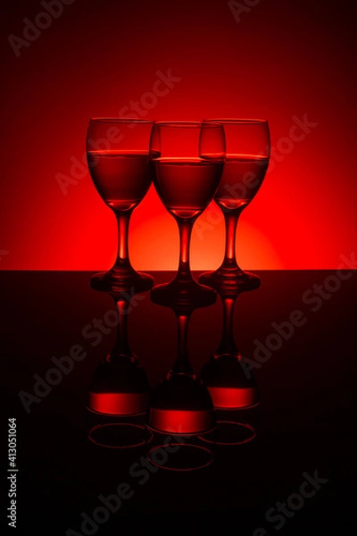 Obraz Filled wine glasses with red background