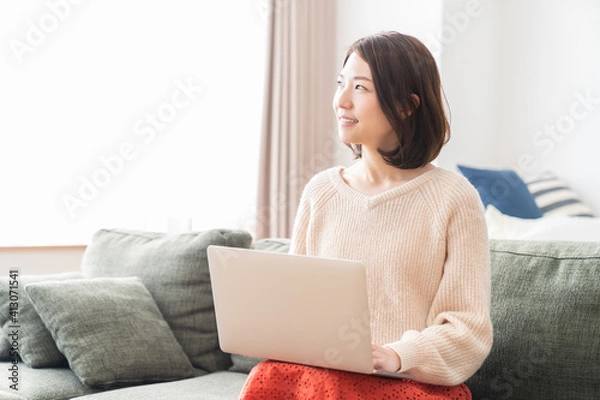 Fototapeta 部屋でラップトップコンピューターを見る女性