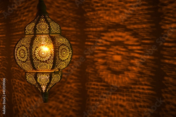 Fototapeta Moroccan golden lamp with circular patterns of light on wall in horizontal position.