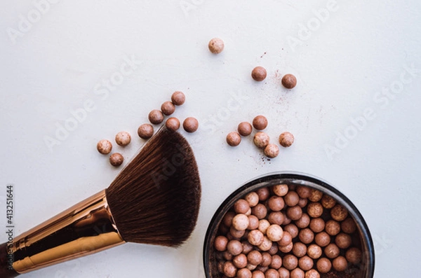 Obraz Powder brush and mixed colored glow face pearls blush on bright background. Top view with copy space.