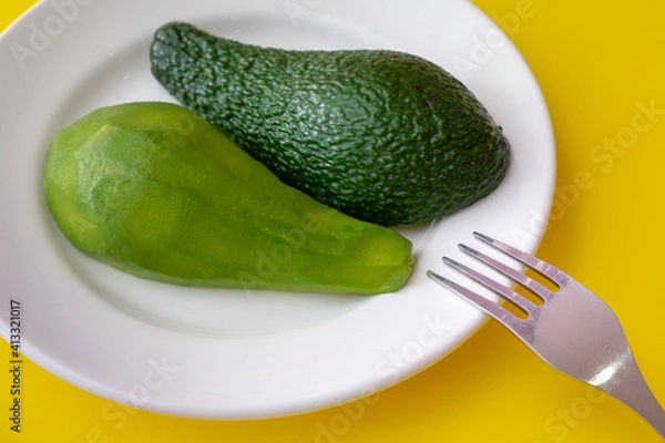 Obraz Avocado slices are on a plate. One slice is peeled. Yellow background