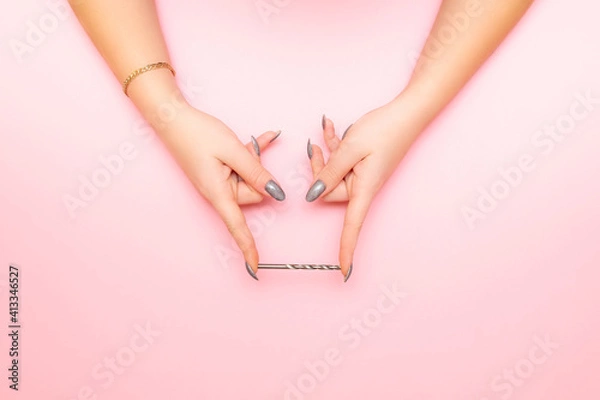 Obraz women's hands hold the drill bit between their fingers. pink background