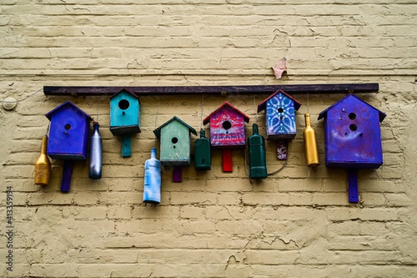 Fototapeta Multicolored art birdhouses composition on the brick wall. Curious installation of wooden bird nests on the house. Selective focus.