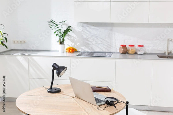 Fototapeta Working from home - a laptop and an organizer on a kitchen table with kitchen in the background.
