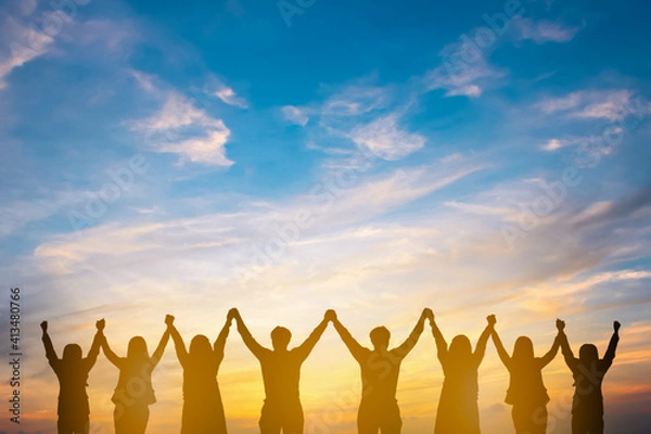 Fototapeta Silhouette of group happy business team making high hands over head in beautiful sunset sky evening time for business success and teamwork concept in company