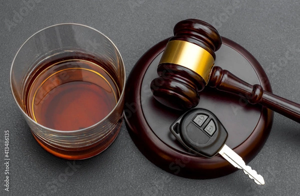 Fototapeta Judge's gavel with car key and glass of whiskey on black.