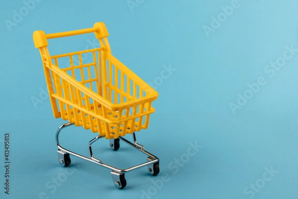 Obraz Empty yellow shopping basket on a blue background. Shopping and crisis concept