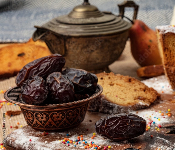Fototapeta A cup of hot tea with dates on wooden background