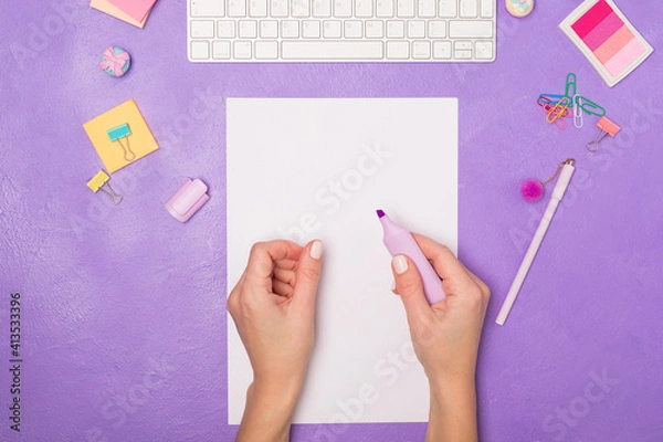 Obraz Bright vivid Flat lay workspace. Woman's hand ready for writing on blank list. Items on bright violet purple background, top view. Girly work desktop. School concept. 