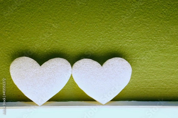 Obraz Two white hearts on light box with green wall background.