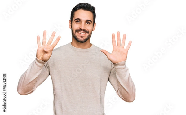 Obraz Young hispanic man wearing casual clothes showing and pointing up with fingers number nine while smiling confident and happy.