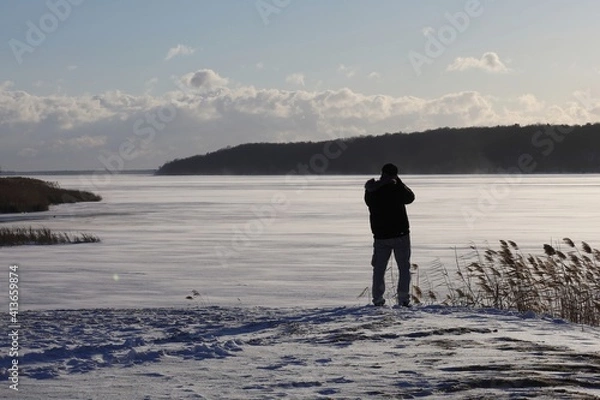 Fototapeta a photographer on a snowy day doing food on a frozen river