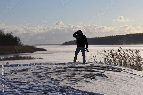 Fototapeta a photographer on a snowy day doing food on a frozen river