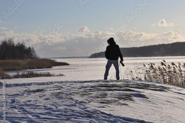 Fototapeta man with a photo camera is walking in winter scenery